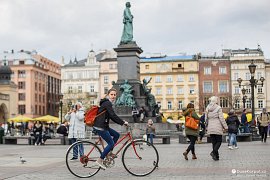 Krakov - hlavní náměstí Rynek Główny, za cyklistkou je pomník Adama Mickiewicza (2017)